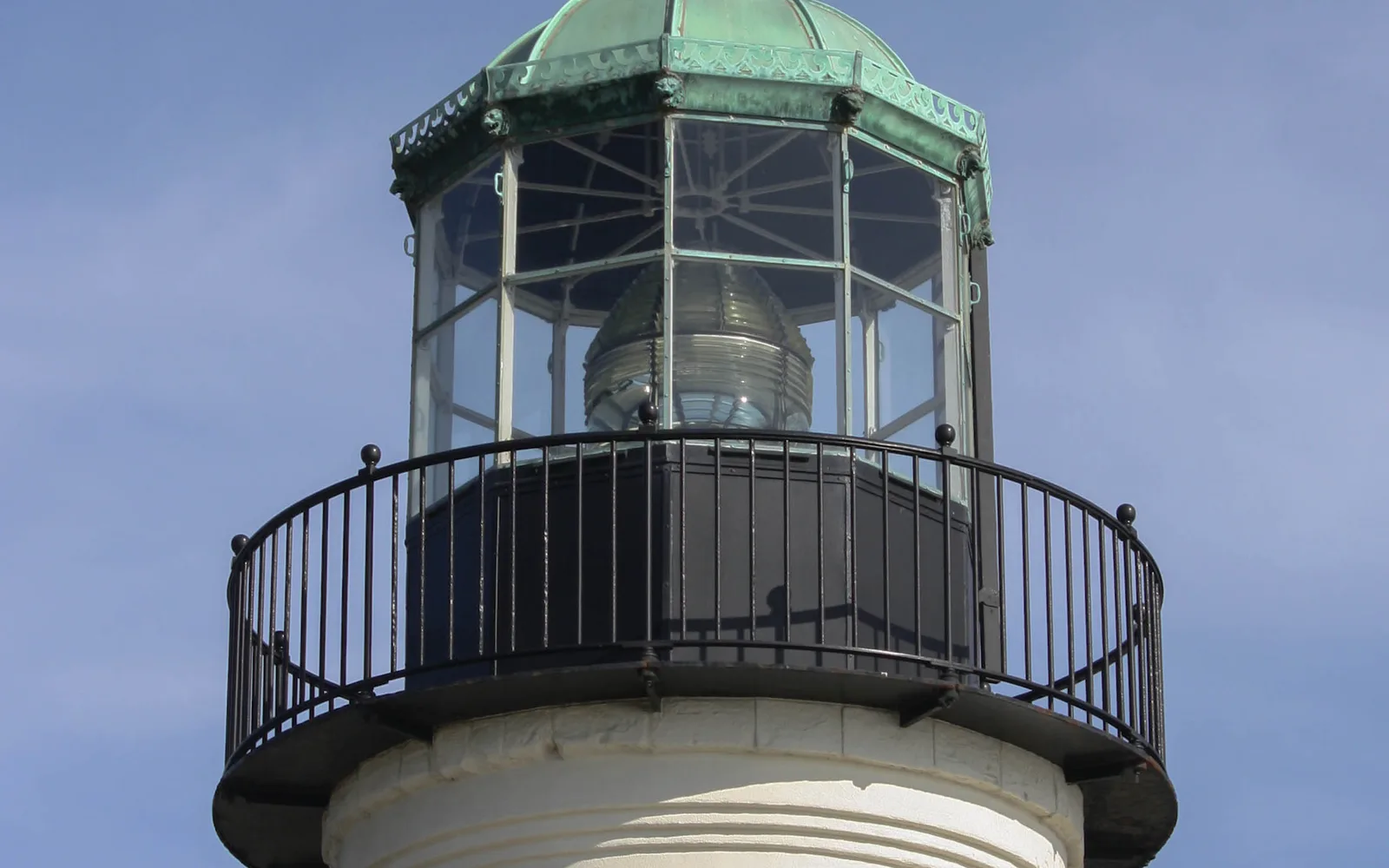 The historic Old Point Loma Lighthouse, a white stone structure, stands on the hillside at Point Loma with San Diego Bay visible in the background