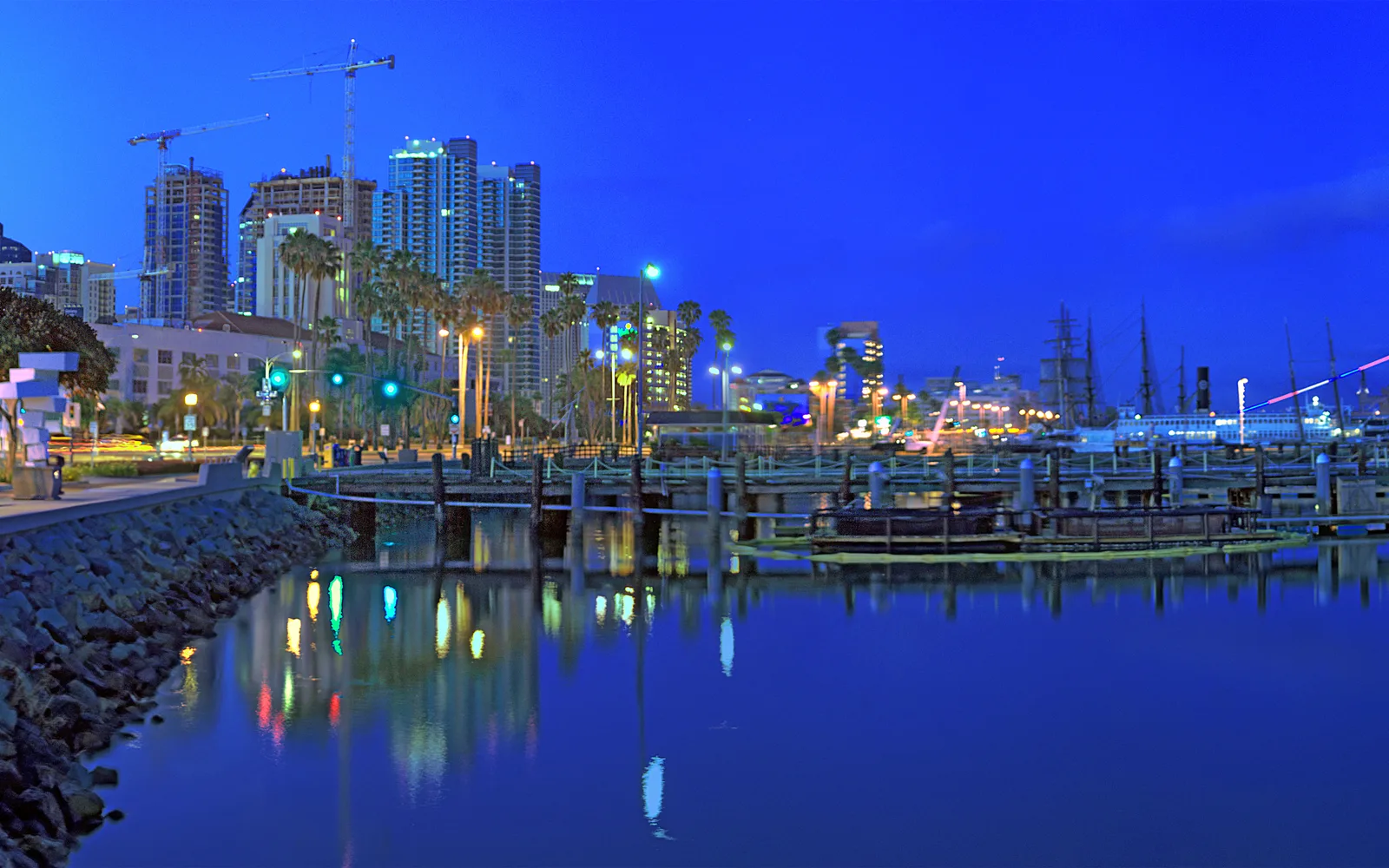 San Diego Harbor at dusk with the illuminated waterfront, city lights reflected in the water, and vessels in the bay